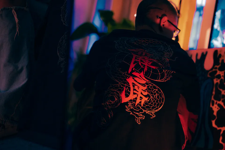 The back print burning red under red light, cigarette smoke at the window