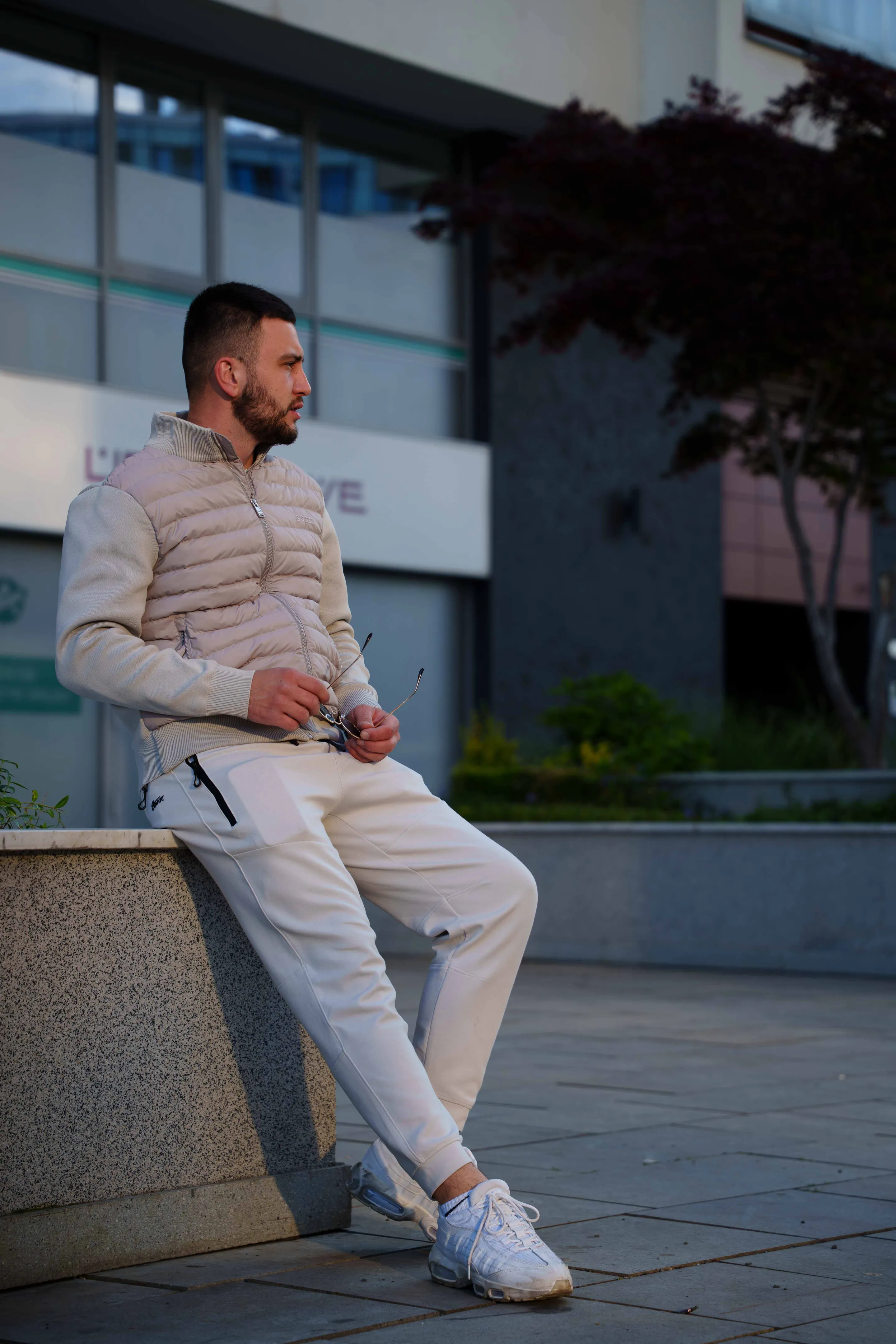 Seated on the granite planter edge, sunglasses in hand