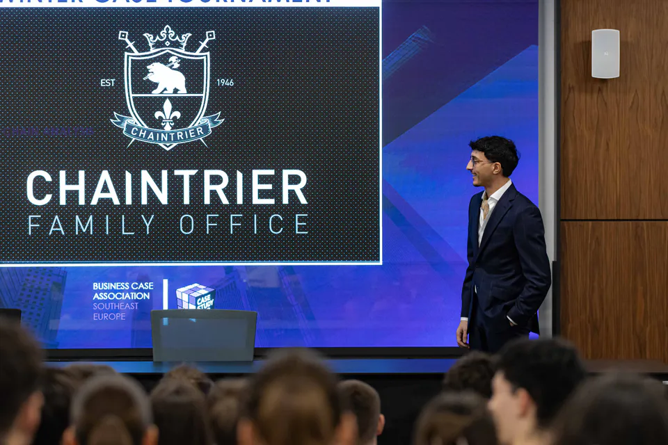 The Chaintrier Family Office crest on the hall screen as a presenter crosses the stage