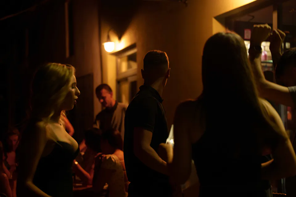 Guests in silhouette against the amber lamplight of the corridor