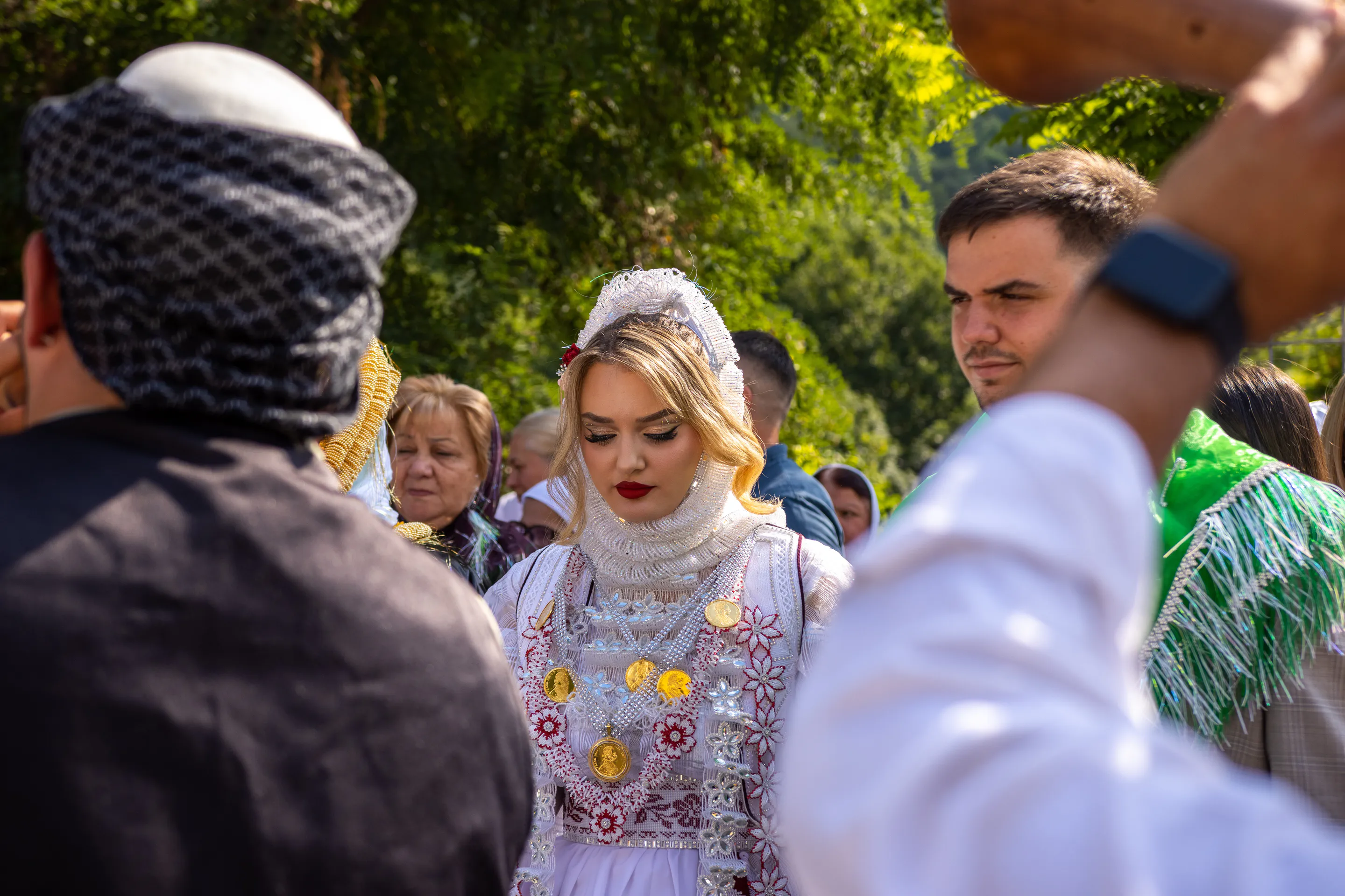 The couple glimpsed between guests' shoulders, a patterned scarf crossing the foreground