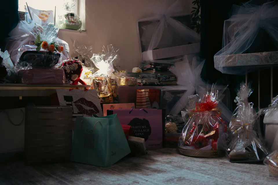 Gift bags and wrapped hampers stacked in the half-dark of the gift room