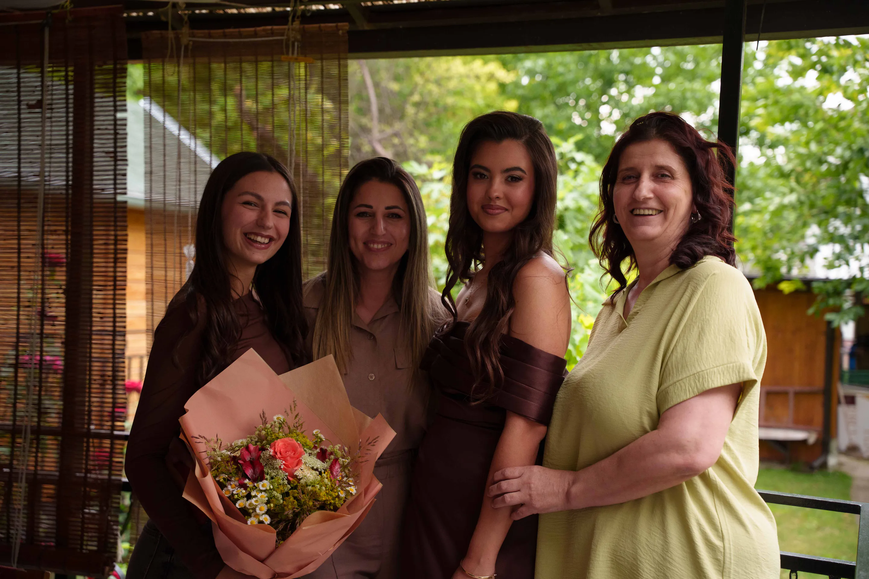 Four women posed together with the bouquet between them
