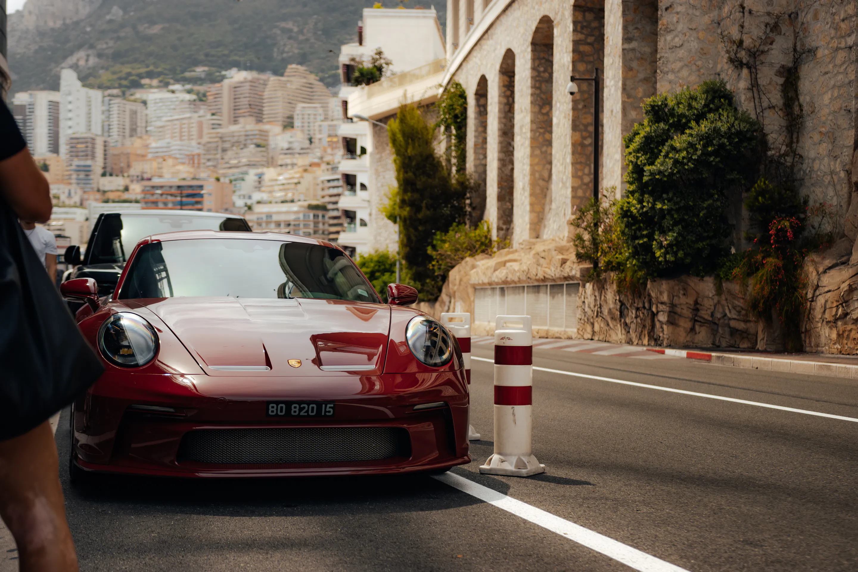 Dark red coupé nosed against a stone archway, hazy skyline behind