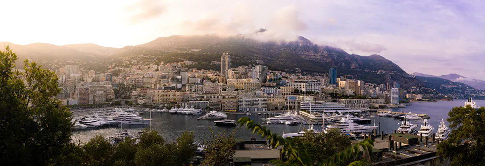 Wide sweep of the marina fronting the hillside city, mist on the ridge